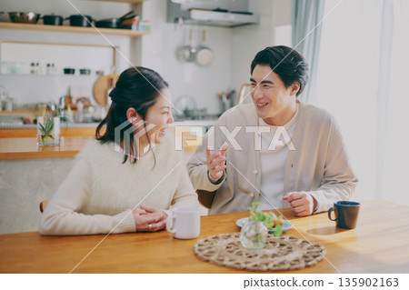 A couple relaxing in the dining room 135902163
