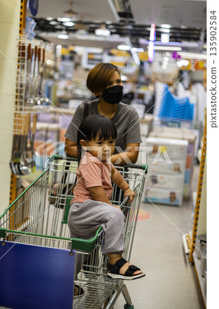 Mom And Child Shop With Cart in Market, A lively ad photo of mom and child shopping with cart in market, hands reaching produce , perfect for family grocery campaign or joyful market documentary. 135902584