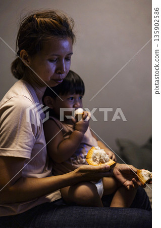 Mom And Toddler Are Eating Santol, A candid documentary shot of mom and toddler sharing santol, seeds on tiny fingers, ideal for parenting ad or pure joy showcase. 135902586