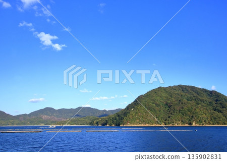 牡蠣筏漂浮在風景如畫的江田島寧靜的景色中,這裡自然資源豐富。 牡蠣筏漂浮在風景如畫的江田島寧靜的景色中,這裡自然資源豐富。 135902831