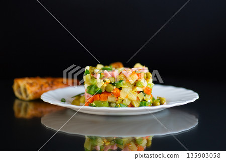 Classic Olivier salad with mixed vegetables on a black background Classic Olivier salad with mixed vegetables on a black background 135903058