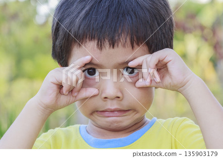 Portrait of happy cute Asian Thai little boy rounding his eyes with his fingers 135903179