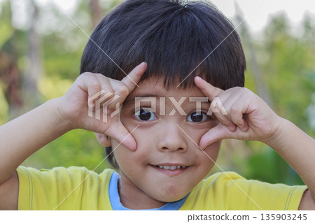 Outdoor portrait head shot of Asian little boy smiling face looking with eyes contact to camera 135903245