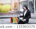 Happy young asian woman holding credit card and using laptop for online shopping in park. 135903370