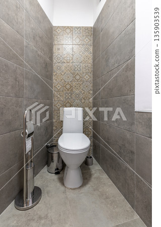 Modern minimalist restroom with white toilet and grey stone tiling Modern minimalist restroom with white toilet and grey stone tiling 135903539