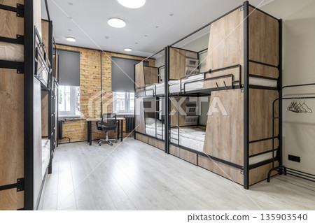 Bright hostel dormitory with modern bunk beds and workspace 135903540