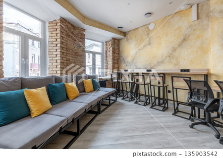Modern hostel common area with sofa and coworking workspace 135903542