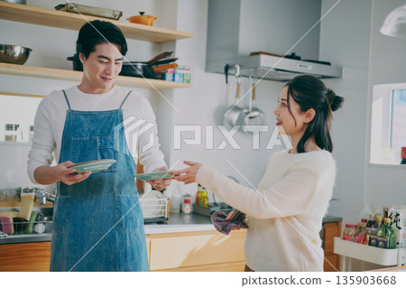 一對夫婦正在收拾碗筷 一對夫婦正在收拾碗筷 135903668
