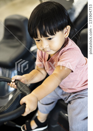 Little One Rides Mower With Joy, a natural light photo portraying innocent play and curiosity as a toddler explores a parked mower at home. Little One Rides Mower With Joy, a natural light photo portraying innocent play and curiosity as a toddler explores a parked mower at home. 135904753