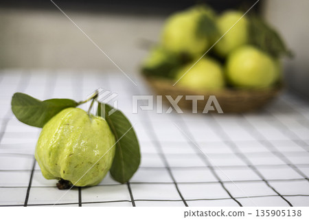 Green Guava In The Bamboo Basket On The Table, A fresh ad photo of green guava in bamboo basket on table, fruits nestled in weave under natural  for tropical harvest or rustic produce documentary. 135905138