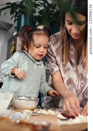 Mom and child make baked goods together in kitchen during afternoon Mom and child make baked goods together in kitchen during afternoon 135906156