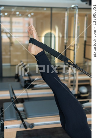 Caucasian woman doing exercises on reformer machine.  135906351