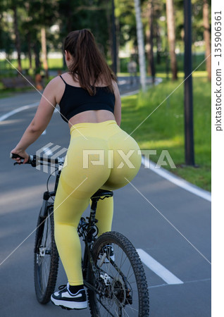 Curvy Caucasian Woman Riding Bicycle in Park. Curvy Caucasian Woman Riding Bicycle in Park. 135906361