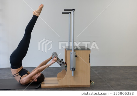Caucasian woman doing Pilates on classic chair. 135906388