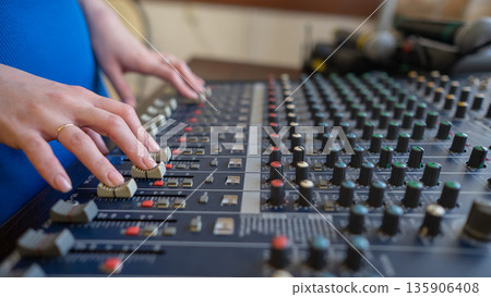 Hands Adjusting Sound Levels on Mixing Console. Hands Adjusting Sound Levels on Mixing Console. 135906408