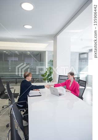 Caucasian man and woman greeting and shaking hands in office. Caucasian man and woman greeting and shaking hands in office. 135906442