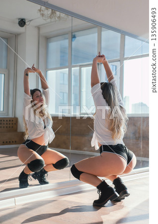 A young woman dances twerk in short shorts in front of a mirror. A young woman dances twerk in short shorts in front of a mirror. 135906493