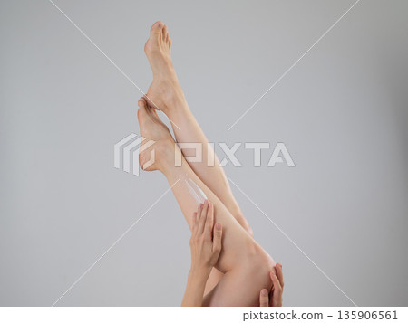 Woman applying moisturizer to her legs. White background.  135906561