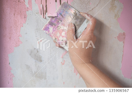 A Hand Using A Paint Stripper To Remove Old Paint From concrete wall. A Hand Using A Paint Stripper To Remove Old Paint From concrete wall. 135906567