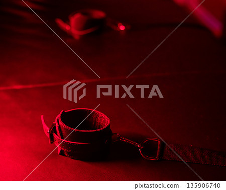 Close-up of leather handcuffs for BDSM games under red light.  135906740