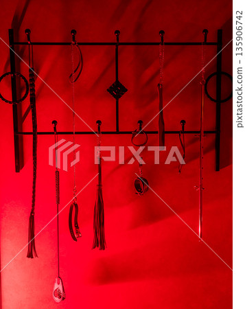 Collection of BDSM toys, whips in red light. Collection of BDSM toys, whips in red light. 135906742
