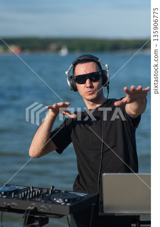 Male DJ playing music on the beach. Male DJ playing music on the beach. 135906775