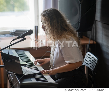 Caucasian woman singing into microphone and playing synthesizer. Online lesson on laptop. Caucasian woman singing into microphone and playing synthesizer. Online lesson on laptop. 135906848