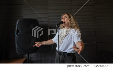 Caucasian woman singing into microphone in music studio.  135906850