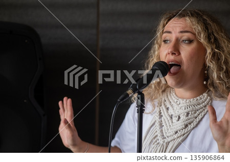 Caucasian woman singing into microphone in music studio. Caucasian woman singing into microphone in music studio. 135906864