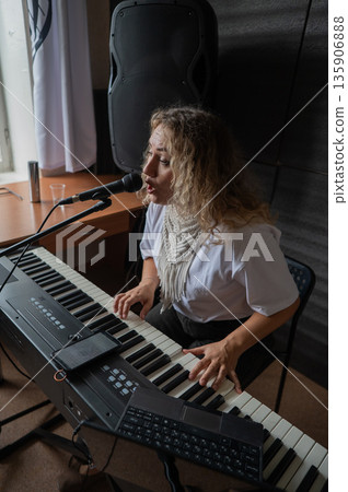 Caucasian woman singing into microphone and playing synthesizer.  135906888