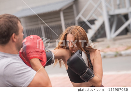Man and woman sparring outdoors. Boxing lesson. Man and woman sparring outdoors. Boxing lesson. 135907086
