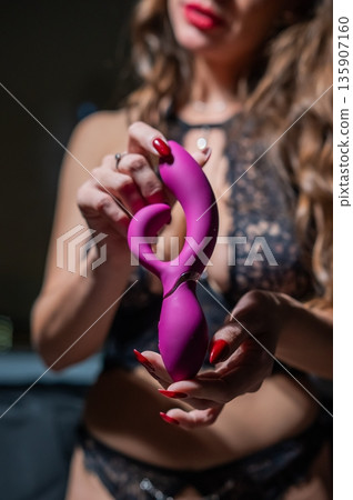 Woman in lace lingerie holds pink dildo. Woman in lace lingerie holds pink dildo. 135907160