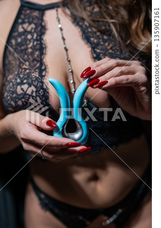 A woman in black lingerie holds a curved vibrator.  135907161