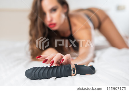 Woman in lace lingerie holds a dildo. Woman in lace lingerie holds a dildo. 135907175