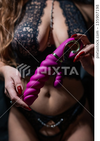 Woman in lace lingerie holds pink dildo. Woman in lace lingerie holds pink dildo. 135907198