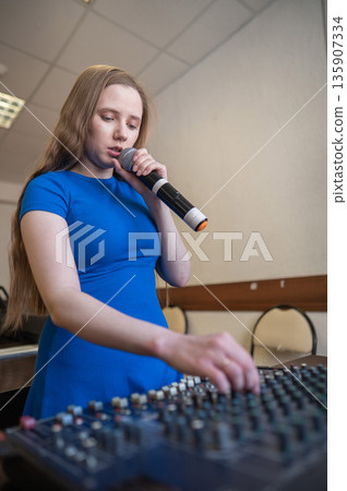 Young woman mixing live sound. Girl recording a song in the studio. Young woman mixing live sound. Girl recording a song in the studio. 135907334