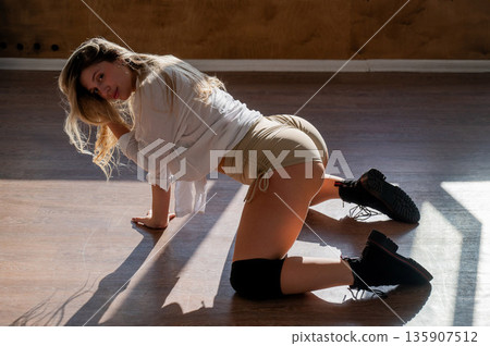 A young woman dances twerk in short shorts on the floor. A young woman dances twerk in short shorts on the floor. 135907512