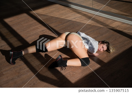 A young woman dances twerk in short shorts on the floor. A young woman dances twerk in short shorts on the floor. 135907515