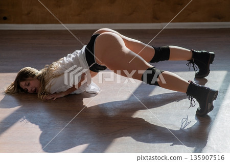 A young woman dances twerk in short shorts on the floor. A young woman dances twerk in short shorts on the floor. 135907516