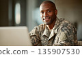 Soldier at a workstation smiling during a break at the military base in the afternoon 135907530