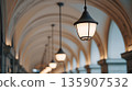 Lights hang from arches in a covered walkway at dusk showcasing design and structure in an urban setting 135907532
