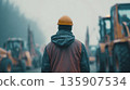 Construction worker looks at heavy machinery in a foggy environment during a morning shift 135907534