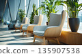 Comfortable chairs positioned near large windows with plants in a bright indoor space during daylight hours 135907538