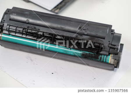 Broken laser printer cartridge on white background.  135907566