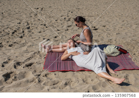 Two Caucasian women relaxing on the beach.  135907568