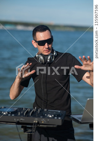 Male DJ playing music on the beach.  135907596