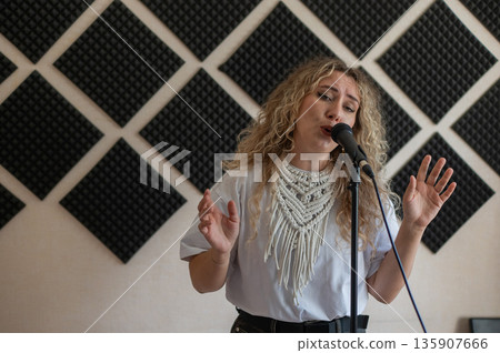 Caucasian woman singing into microphone in music studio. Caucasian woman singing into microphone in music studio. 135907666