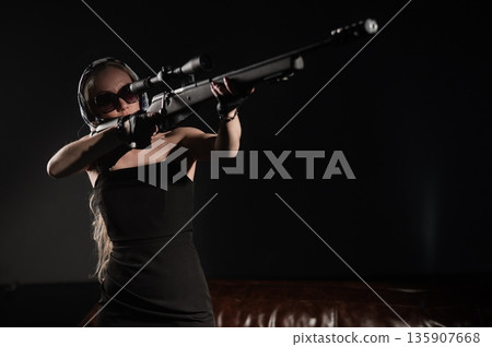 A Caucasian woman practicing shooting with a rifle and scope.  135907668