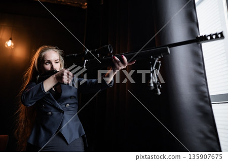 A Caucasian woman in a business suit holds a rifle with a scope. A Caucasian woman in a business suit holds a rifle with a scope. 135907675