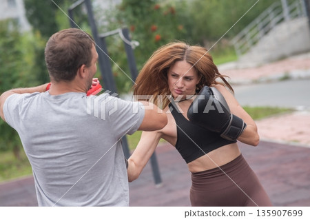 Man and woman sparring outdoors. Boxing lesson. 135907699